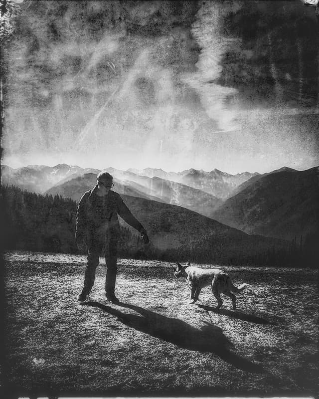 Black-and-white mountain landscape with a figure and dog
